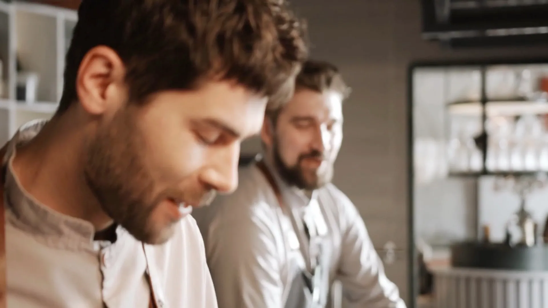 To smilende medarbejdere arbejder side om side i et restaurantkøkken